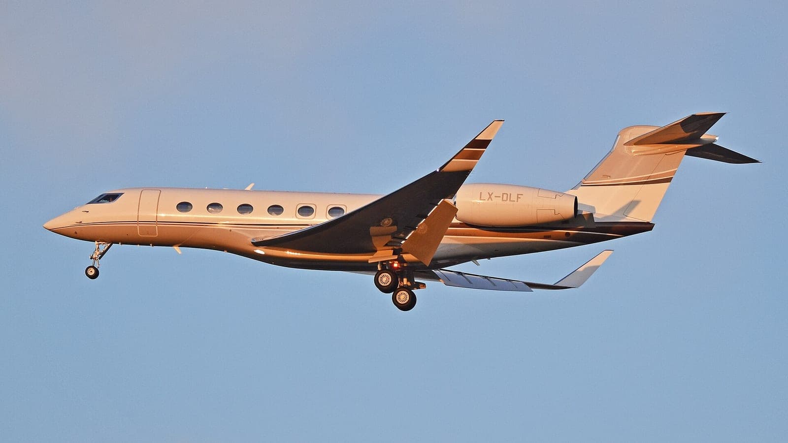A Luxembourg-registered Gulfstream G650, LX-DLF, on final approach to Milan Malpensa in low evening light, gear down against a clear sky.