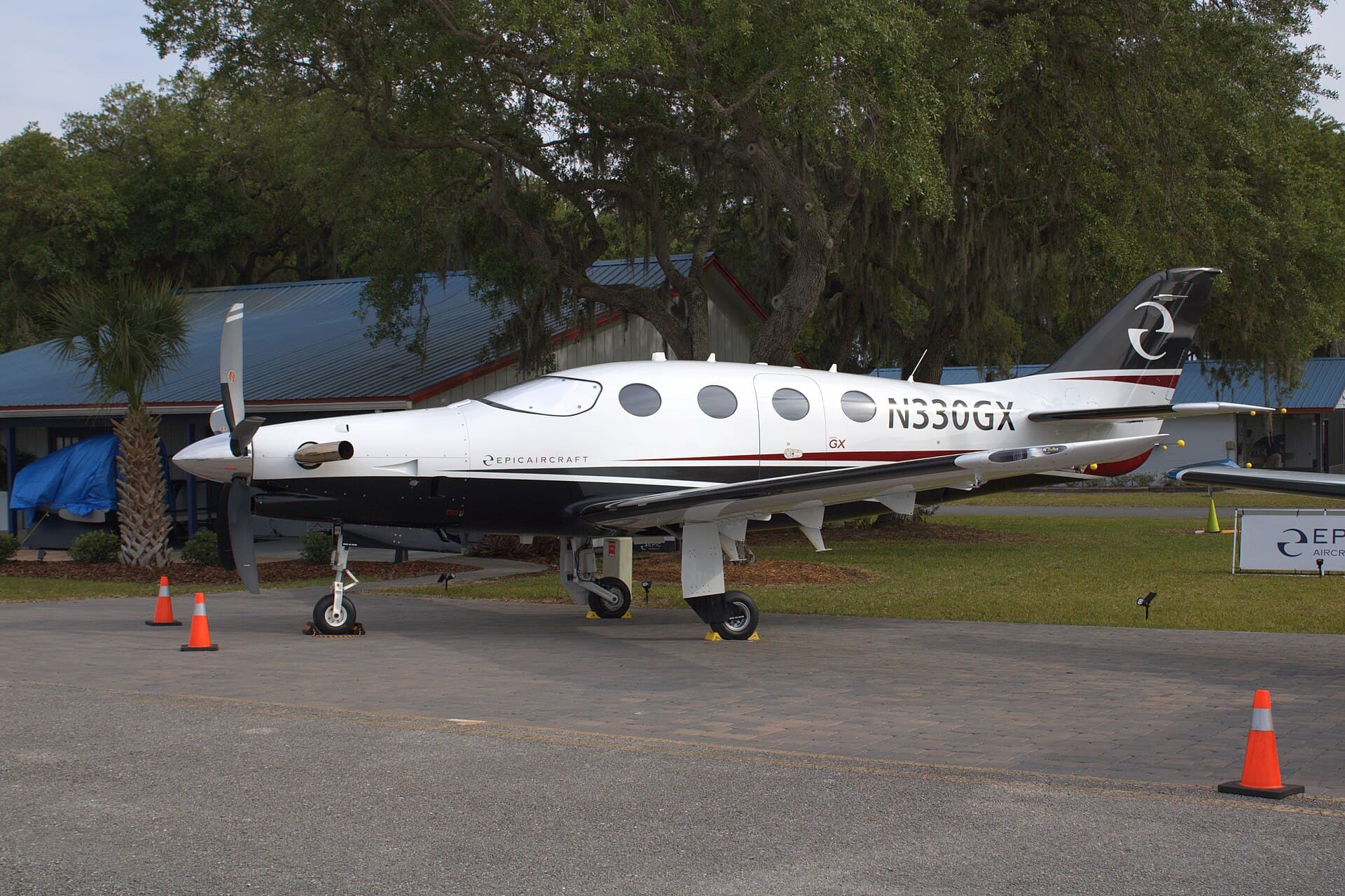 An Epic E1000 GX single-engine turboprop, registration N330GX, parked on the ramp at Lakeland Linder International Airport during the 2024 Sun 'n Fun show, its five-blade propeller and swept tail visible in daylight.