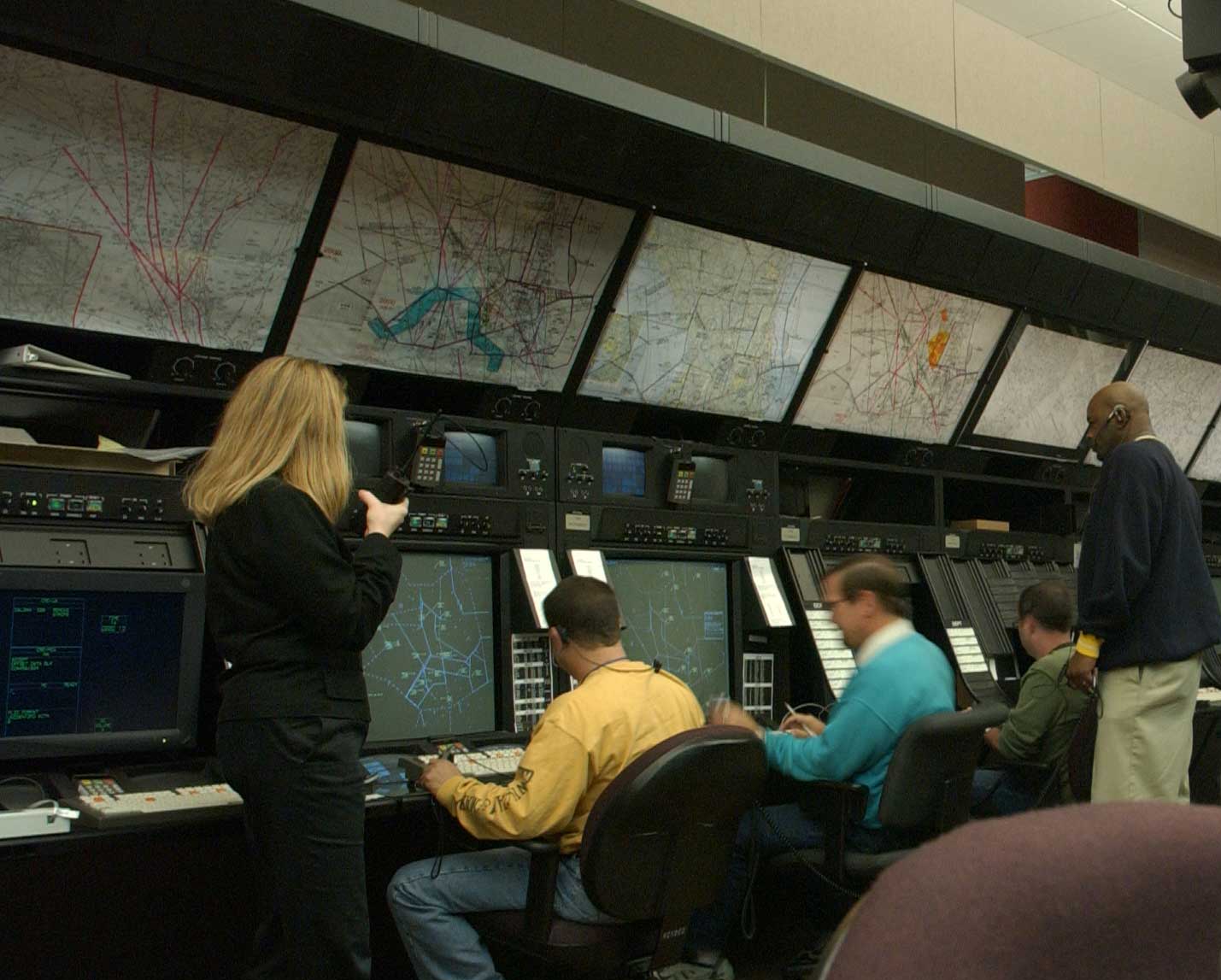 Air route traffic controllers working at their radar consoles inside the FAA's Washington Air Route Traffic Control Center, in the low ambient light of the operations floor.