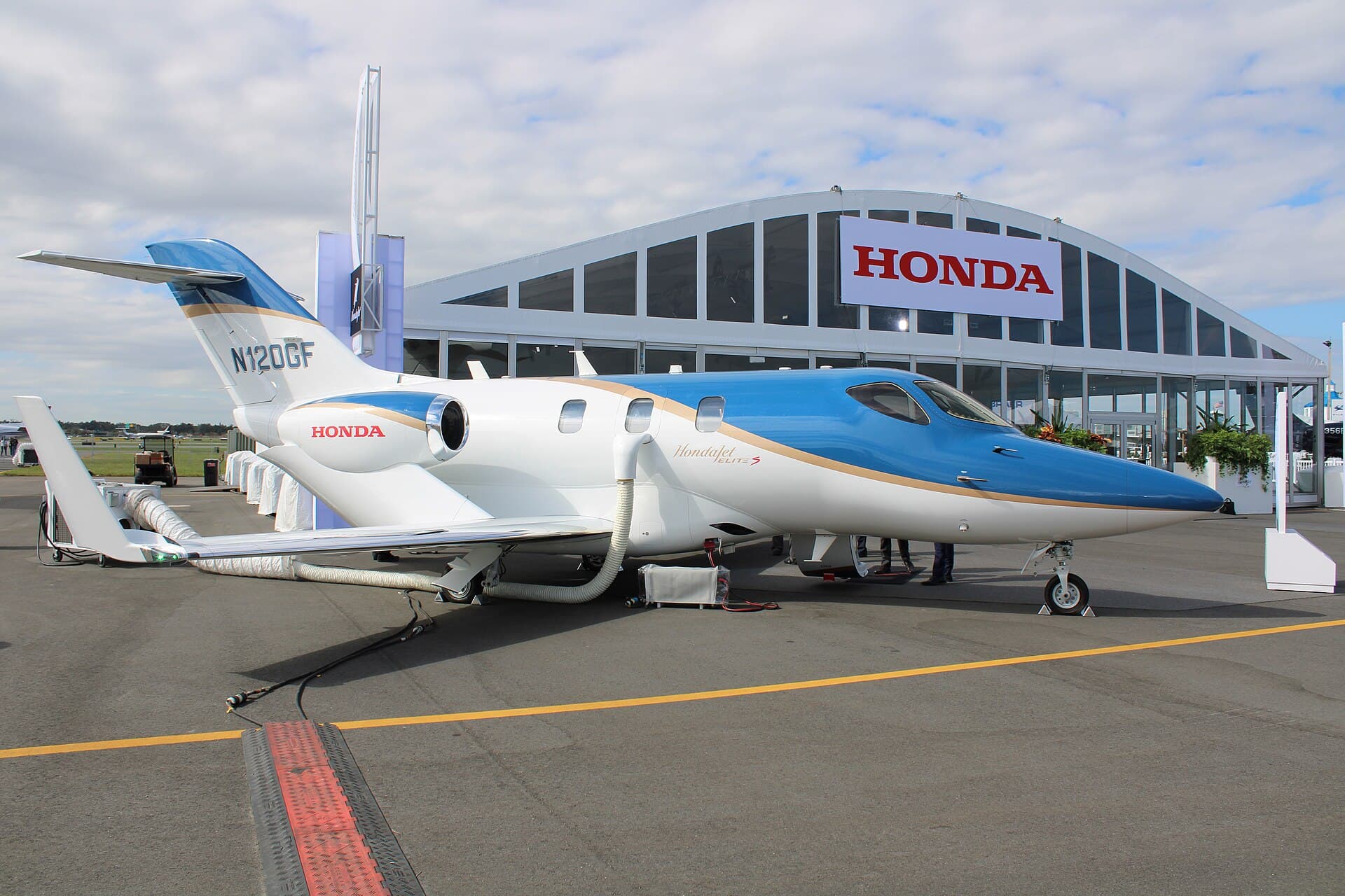A Honda HA-420 HondaJet Elite S business jet, registration N120GF, parked on the ramp with its distinctive over-the-wing engine mounts visible, on static display at the 2022 NBAA-BACE convention at Orlando Executive Airport in daylight.