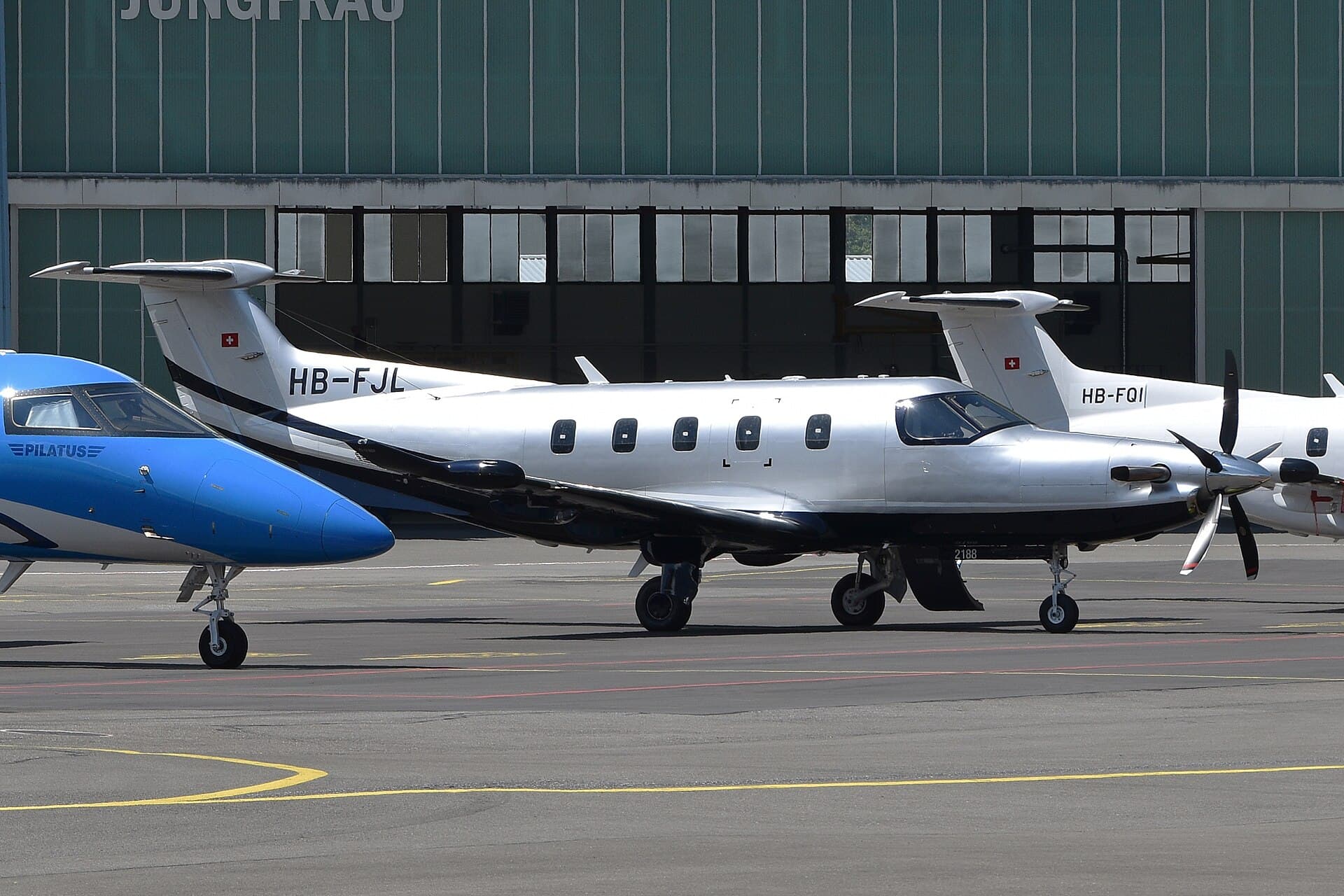 A Pilatus PC-12 NGX single-engined turboprop, registration HB-FJL, parked on the apron at Buochs airfield in Switzerland, photographed from the right side with its four-blade propeller stationary.
